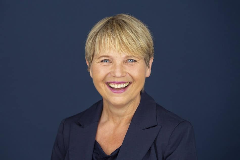 Positive Frau im Businessoutfit, die lächelnd in die Kamera schaut, symbolisiert Coaching, Persönlichkeitsentwicklung und professionelle Beratung. - Kontakt- und Coachingorte